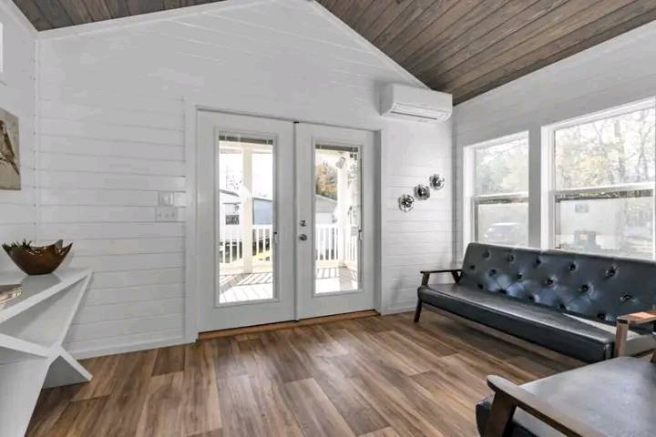 Spacious living room with rustic wooden flooring, a large beige sectional sofa, and a modern fireplace. Neutral tones create a cozy ambiance.