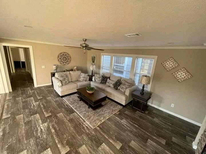 Modern living room with gray sectional sofa and patterned cushions, centered with a wooden coffee table on a rug. Wooden floor, wall art, and soft lighting create a cozy ambiance.