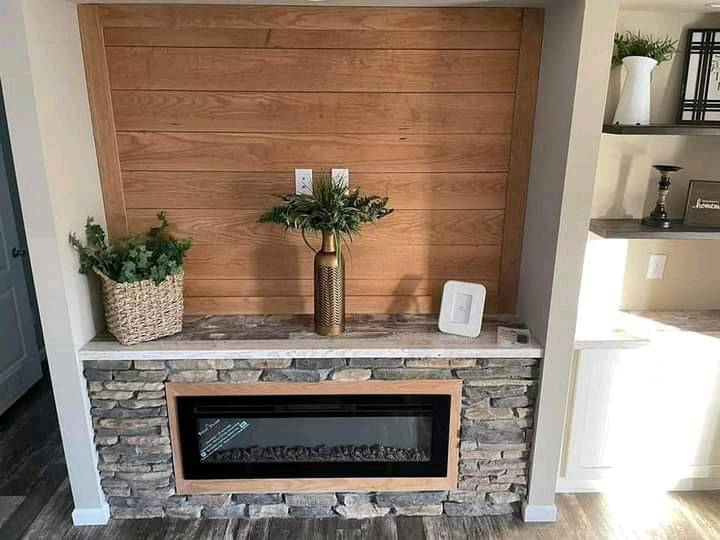 A bright hallway with white walls and dark wooden flooring. A white desk with a green chair is against the wall, with shelves holding books and decor.