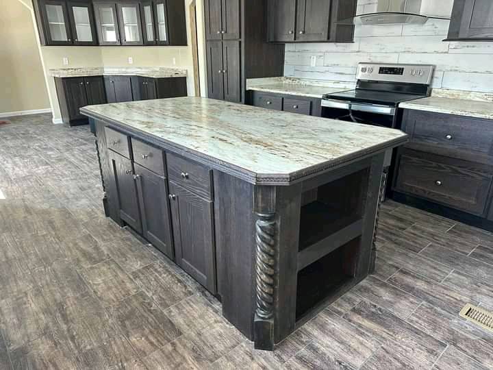 Spacious kitchen with dark wood cabinets and a central island. Granite countertops and stainless steel appliances create a modern, elegant look.