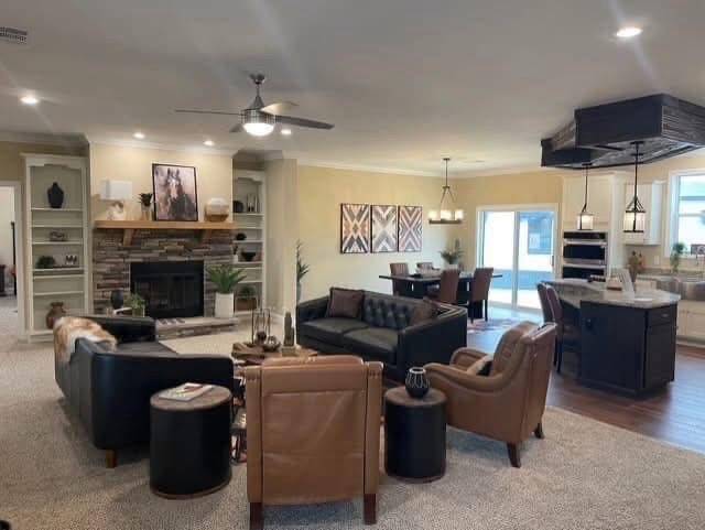 Spacious living room with modern decor. Features a stone fireplace, leather chairs, a black sofa, and a dining area with pendant lighting. Warm, inviting ambiance.