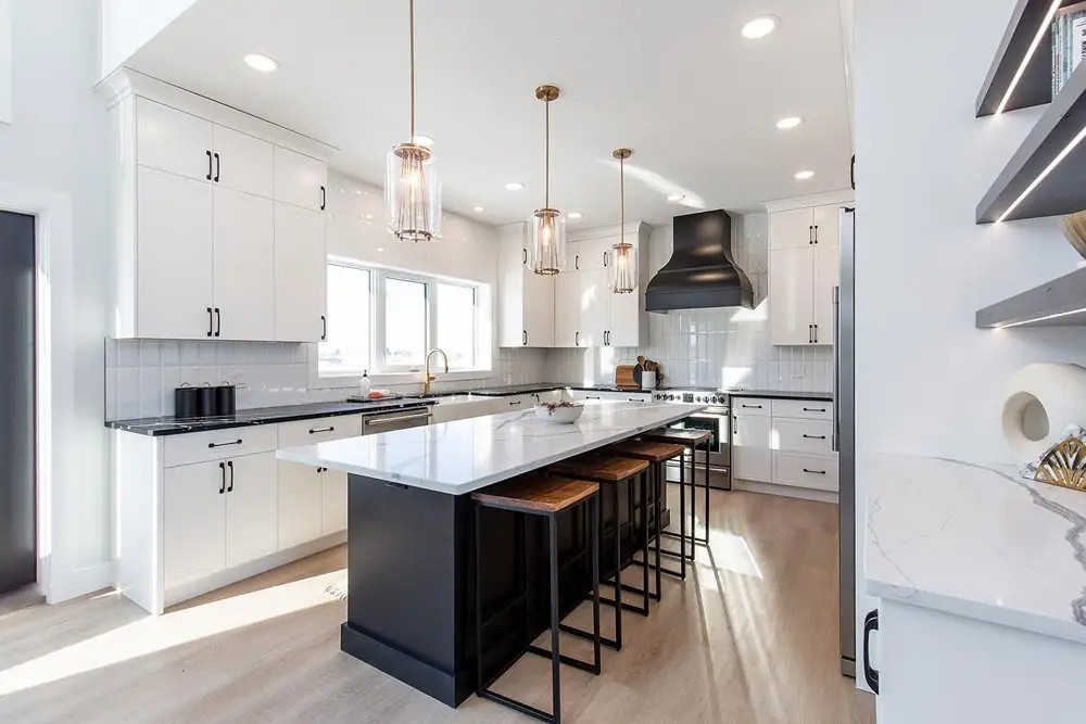 Sleek modern kitchen with white cabinets, large black island, wooden stools, pendant lights, and a black range hood. Bright natural light, airy ambiance.