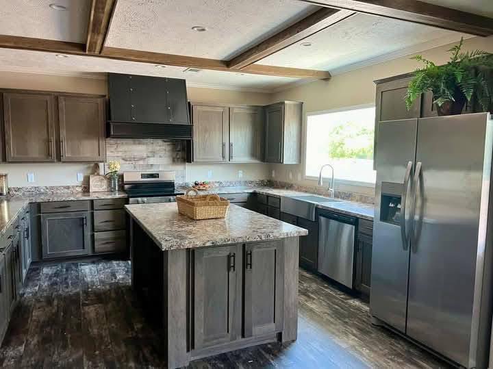 Modern kitchen with dark wooden cabinets, a large marble island, and stainless steel appliances. Sunlight streams through a window, creating a warm, inviting atmosphere.