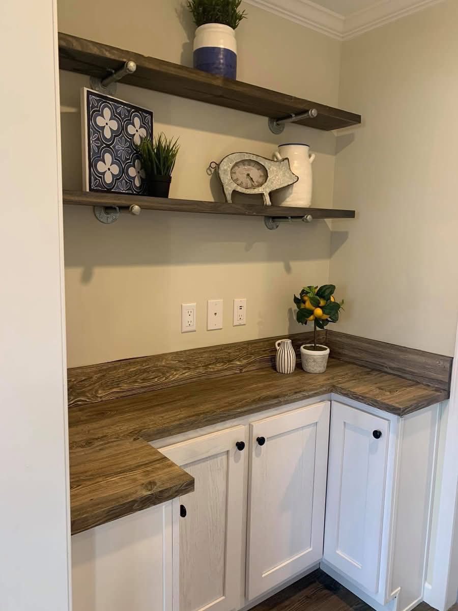 Cozy kitchen nook with wood cabinets and shelves. Decor includes a ceramic pig, potted plants, and a citrus tree adding a touch of nature.