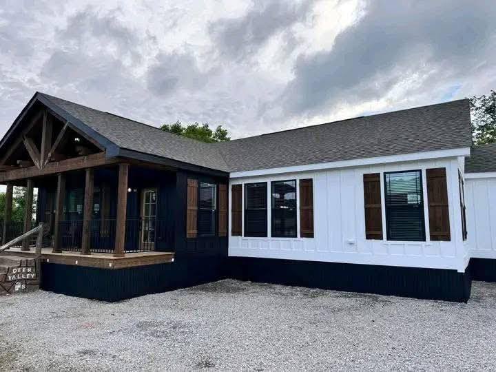 Modern single-story house with a dark porch, white siding, and dark shutters. Overcast sky sets a calm tone. "Deer Valley" sign visible.