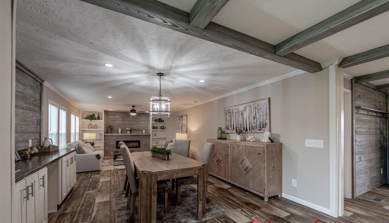 Spacious living room with rustic decor, featuring a wooden dining table, a modern chandelier, a cozy seating area, and a fireplace, all in neutral tones.
