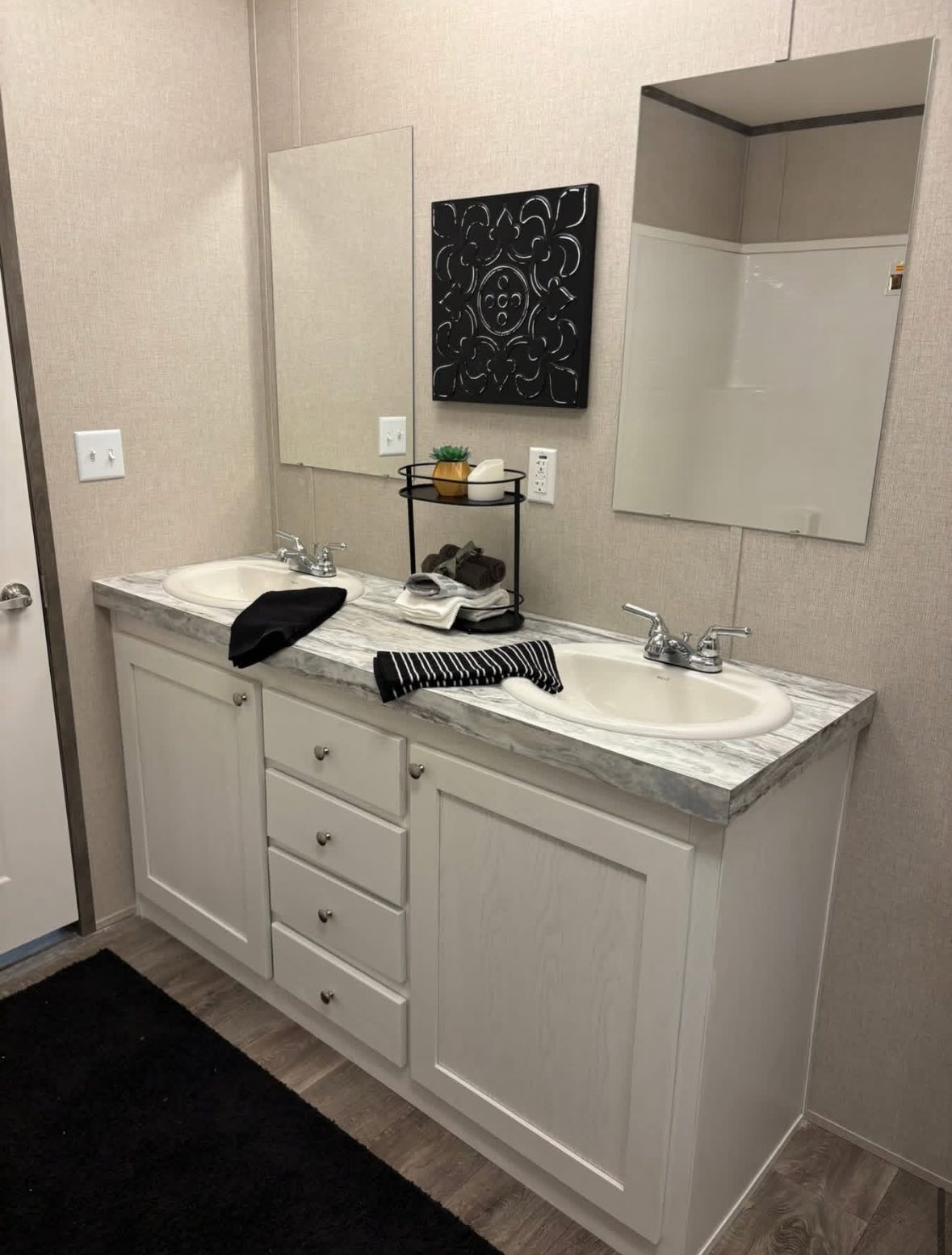 Double bathroom vanity with white cabinets and marble countertop. Two mirrors and a decorative black wall art above. Minimalist and modern feel.