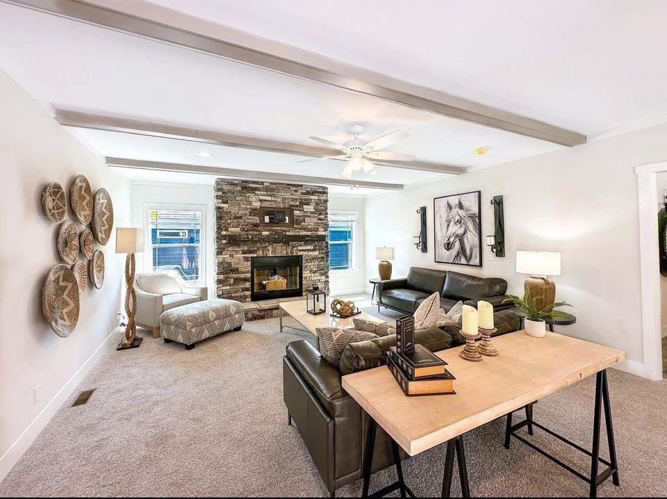Cozy living room with modern flair, featuring stone fireplace, leather sofas, and wooden table. Wall decor includes woven baskets and horse artwork.