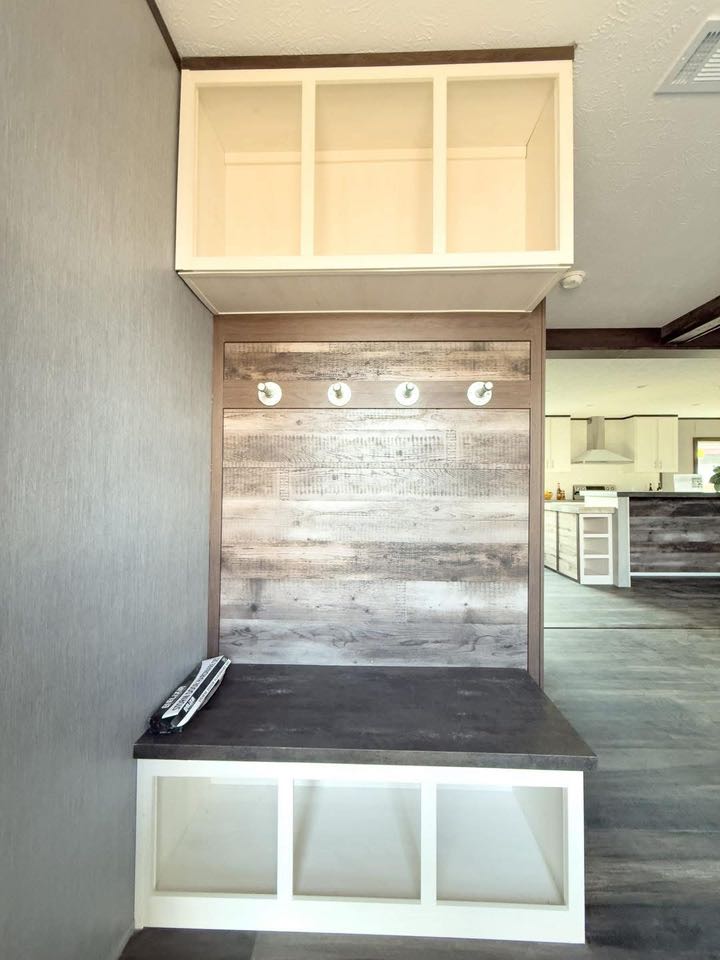 Modern entryway with a rustic wood accent, featuring four coat hooks and open storage cubbies above and below. The space feels welcoming and organized.