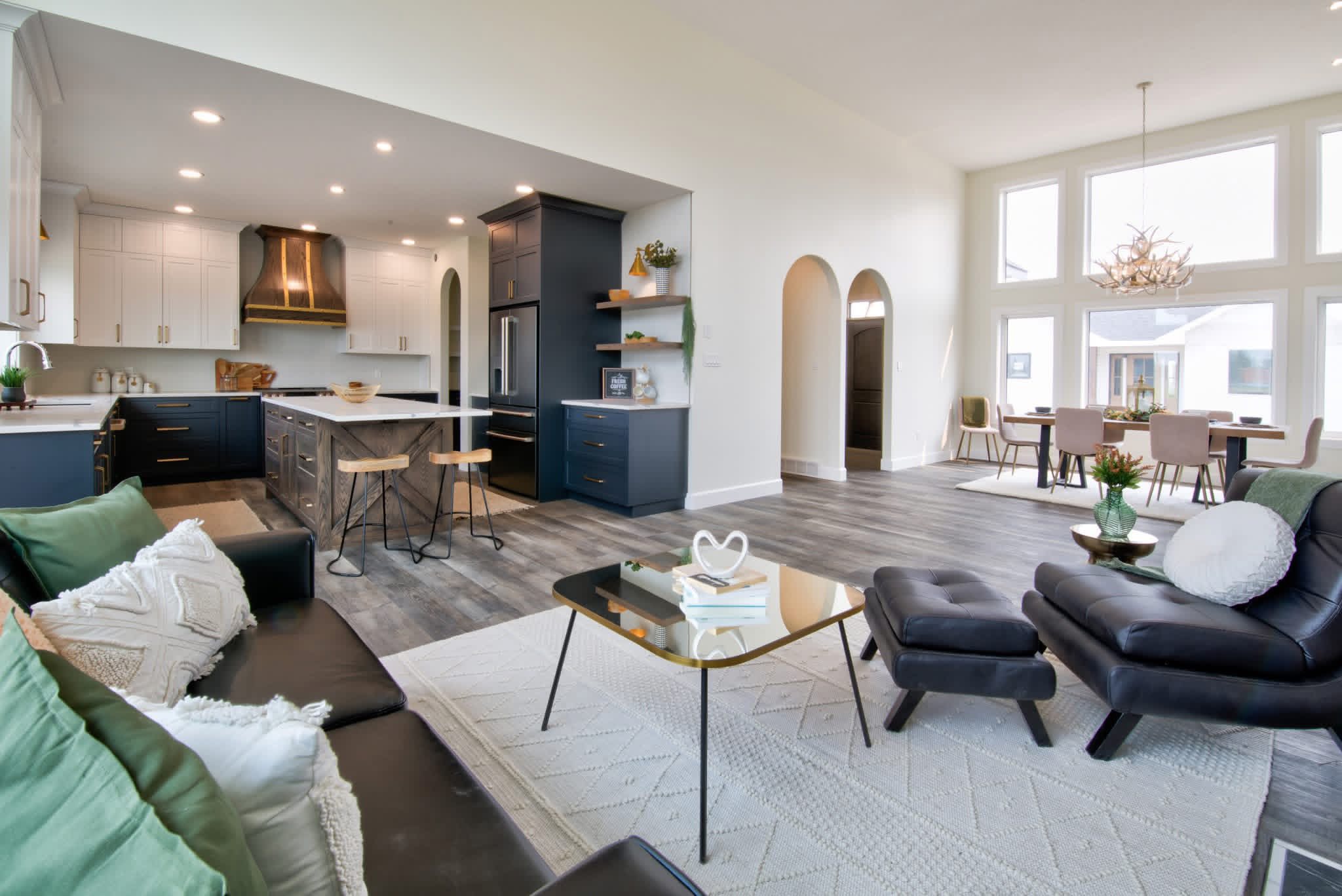 Modern open living space with a cozy lounge area, sleek kitchen, and elegant dining room. Neutral tones and ample natural light convey warmth.