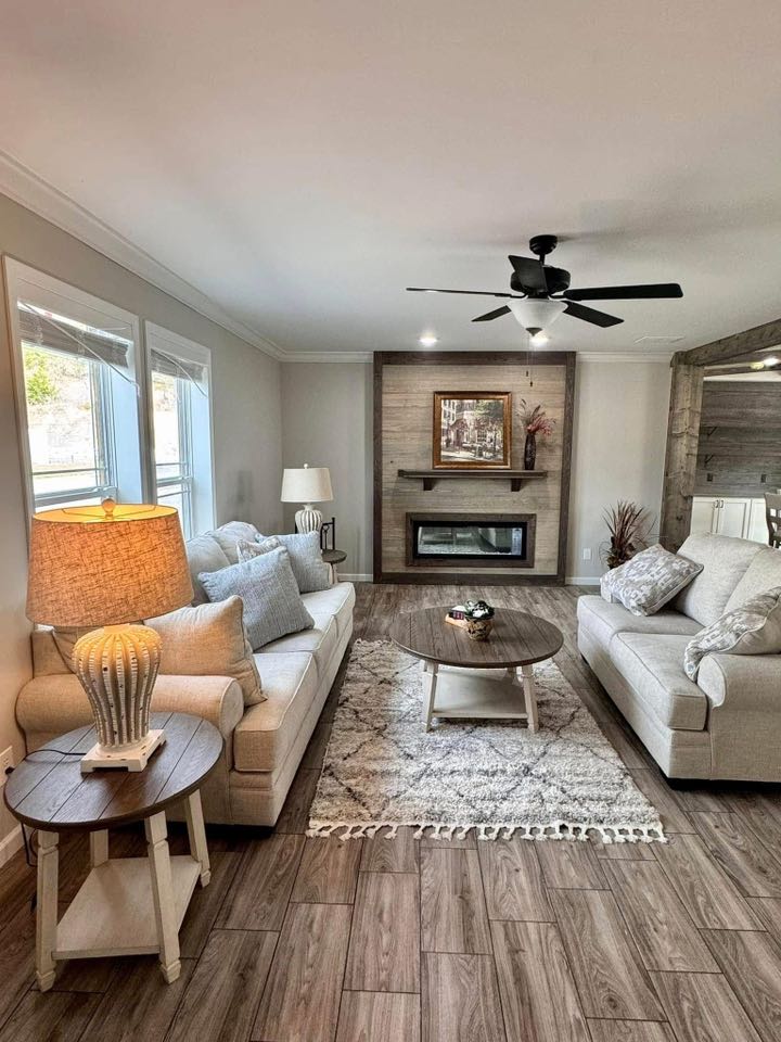 Cozy living room with beige sofas, a wooden coffee table on a patterned rug, a modern fireplace, and soft lighting, creating a warm and inviting ambiance.
