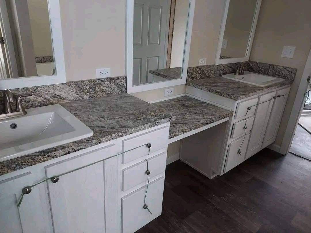 Bathroom vanity with two white sinks, marble countertops, and beige cabinets. Mirrors above each sink, neutral tones, modern and clean design.
