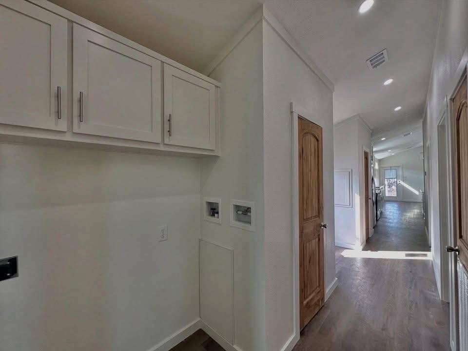A bright hallway with wooden doors and white cabinetry. Sunlight streams in, highlighting the wooden floor and creating a warm, inviting atmosphere.