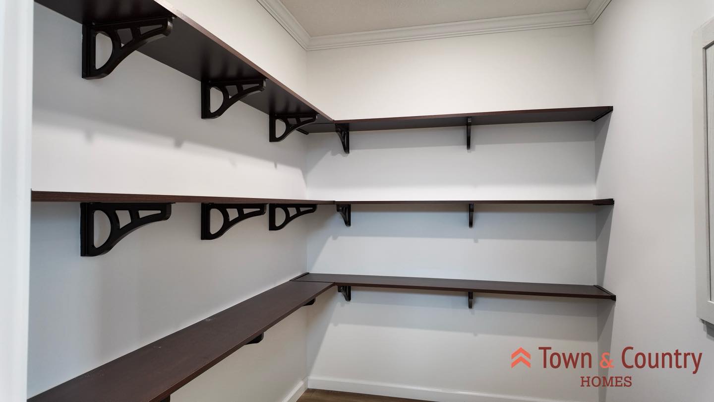 Empty pantry with wooden shelves against white walls, neatly arranged in parallel rows. The space is simple, organized, and functional, with ample storage.