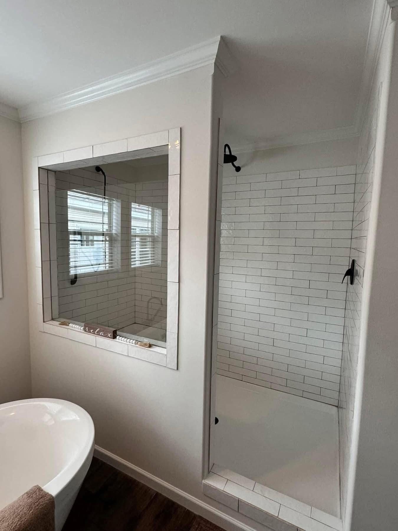 Modern bathroom with a large glass shower, white subway tiles, and a freestanding bathtub. The space feels clean and tranquil, with soft lighting.