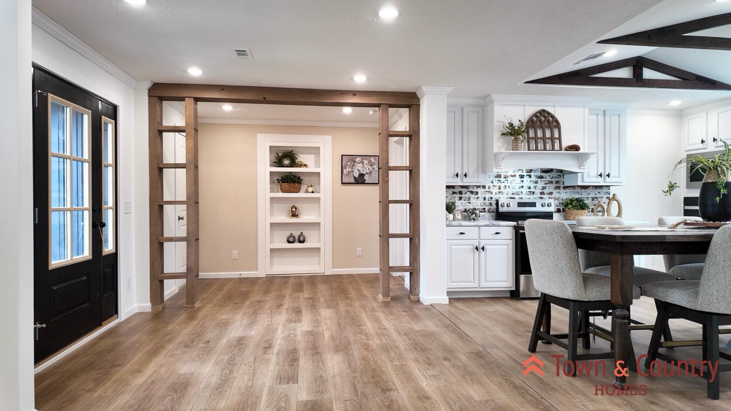 Stylish open-concept kitchen with white cabinets, light wood flooring, and a farmhouse table. Cozy, inviting, and perfect for gatherings.