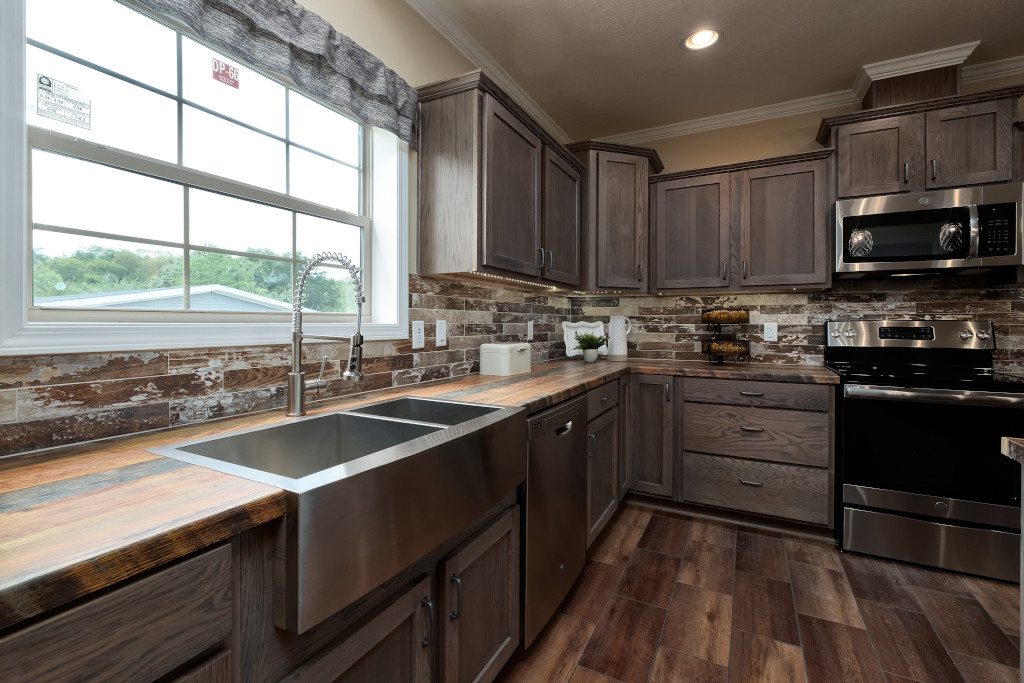 Modern kitchen with rustic elements. Features stainless steel appliances, wood cabinets, and a farmhouse sink. Warm, inviting ambiance with natural light.