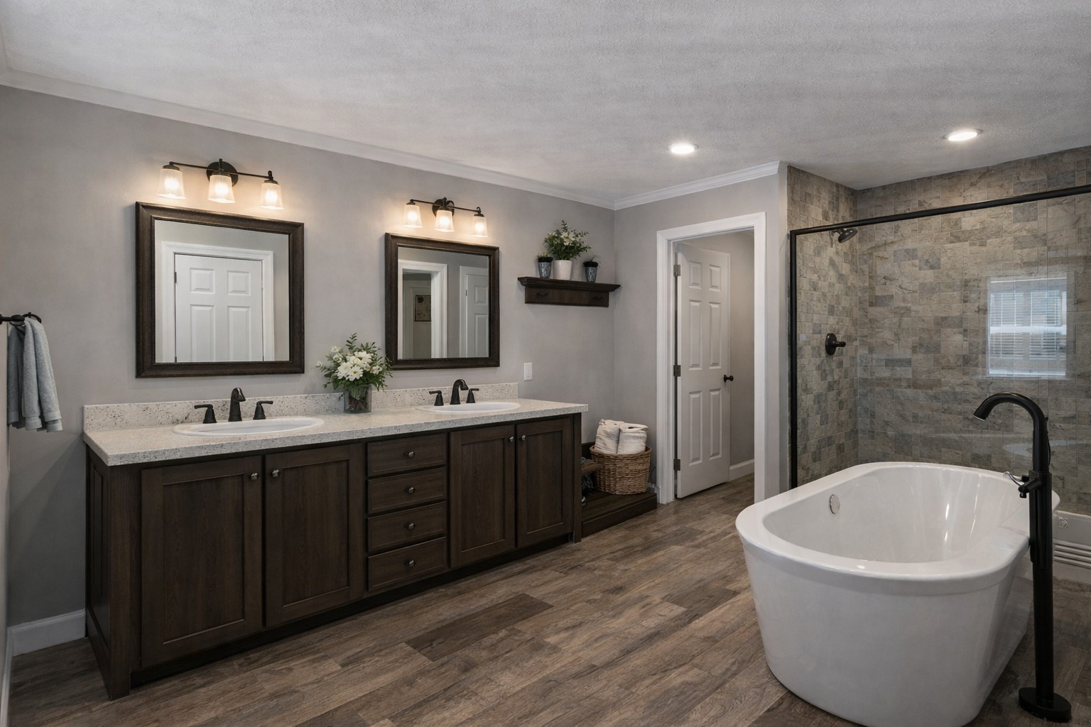 Elegant bathroom with dark wood double vanity and large framed mirrors under warm lights. Features a freestanding tub and a spacious glass shower.