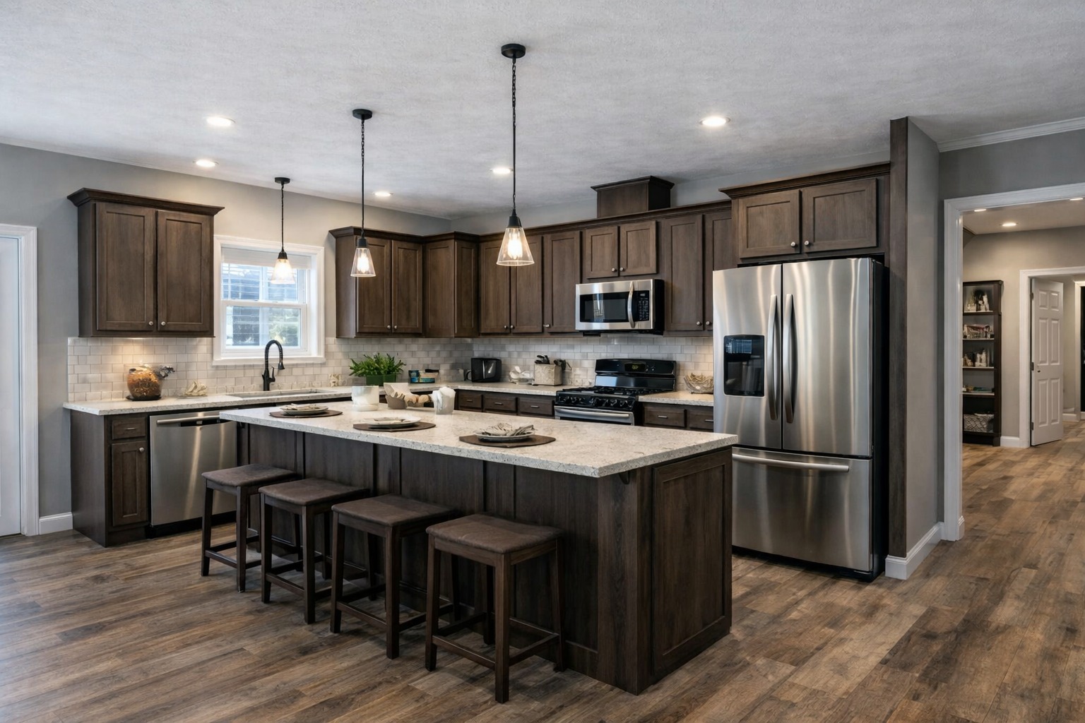 Spacious kitchen with dark wood cabinets, stainless steel appliances, and a large island with stools. Warm lighting and wooden flooring create a cozy atmosphere.