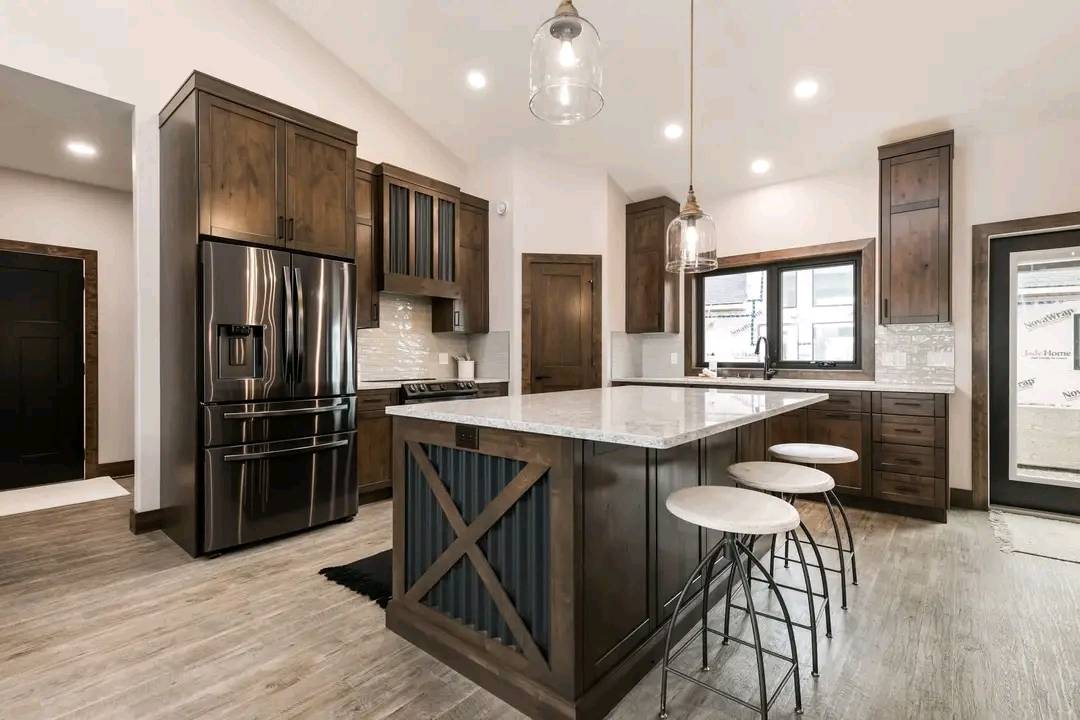 Modern kitchen with wooden cabinets, white marble island, and three bar stools. Stainless steel appliances and pendant lights create a warm, inviting atmosphere.