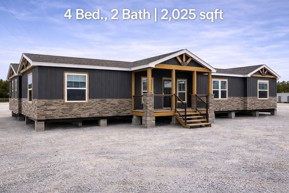 Modular home with dark gray siding, stone accents, and a wooden porch. It features 4 bedrooms, 2 bathrooms, totaling 2,025 sq ft, set on a gravel lot.