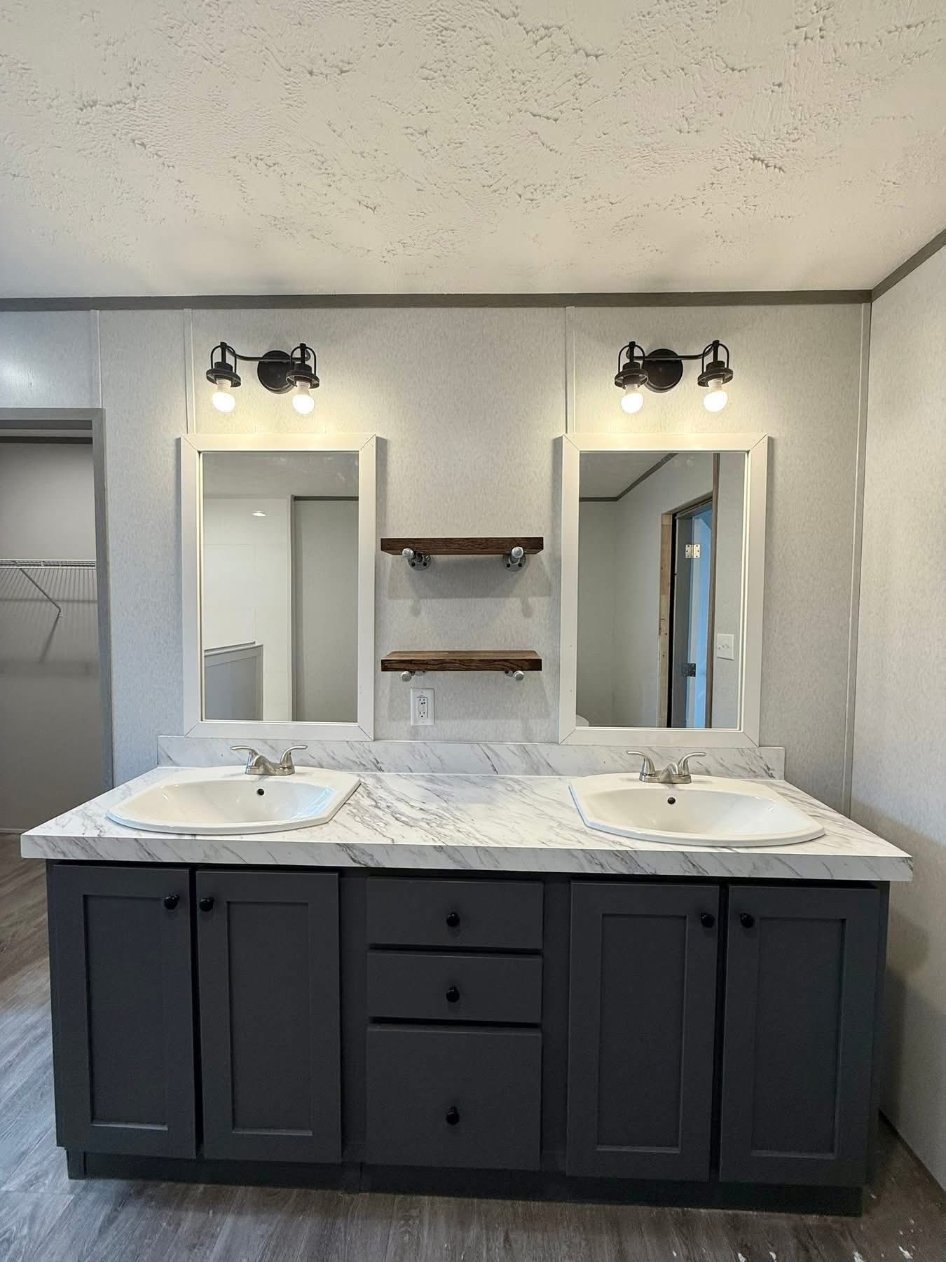 Elegant bathroom with dual sinks on a white marble countertop, gray cabinet, and matching mirrors. Black light fixtures add a modern touch.