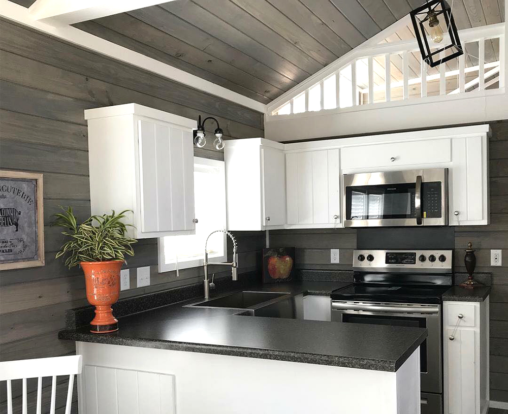 Cozy kitchen with white cabinets, dark countertops, and stainless steel appliances. A vase with a plant sits on the counter, exuding a warm, inviting atmosphere.