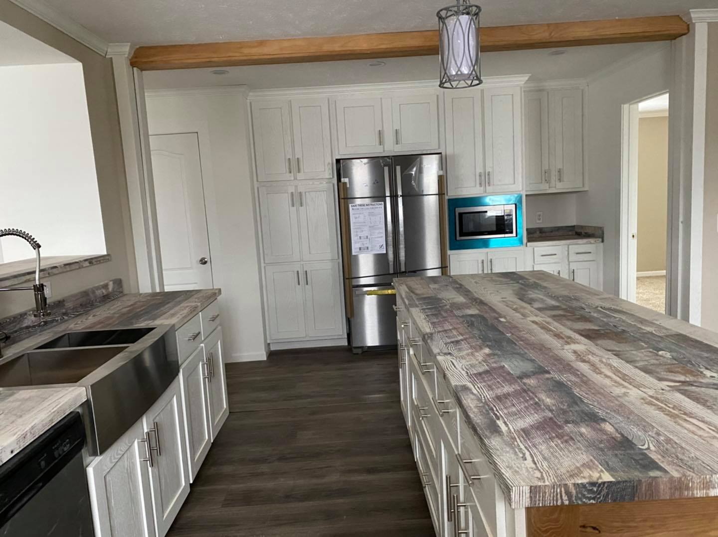 Modern kitchen with white cabinets, stainless steel appliances, and a rustic wooden island. A pendant light hangs overhead, conveying a cozy ambiance.
