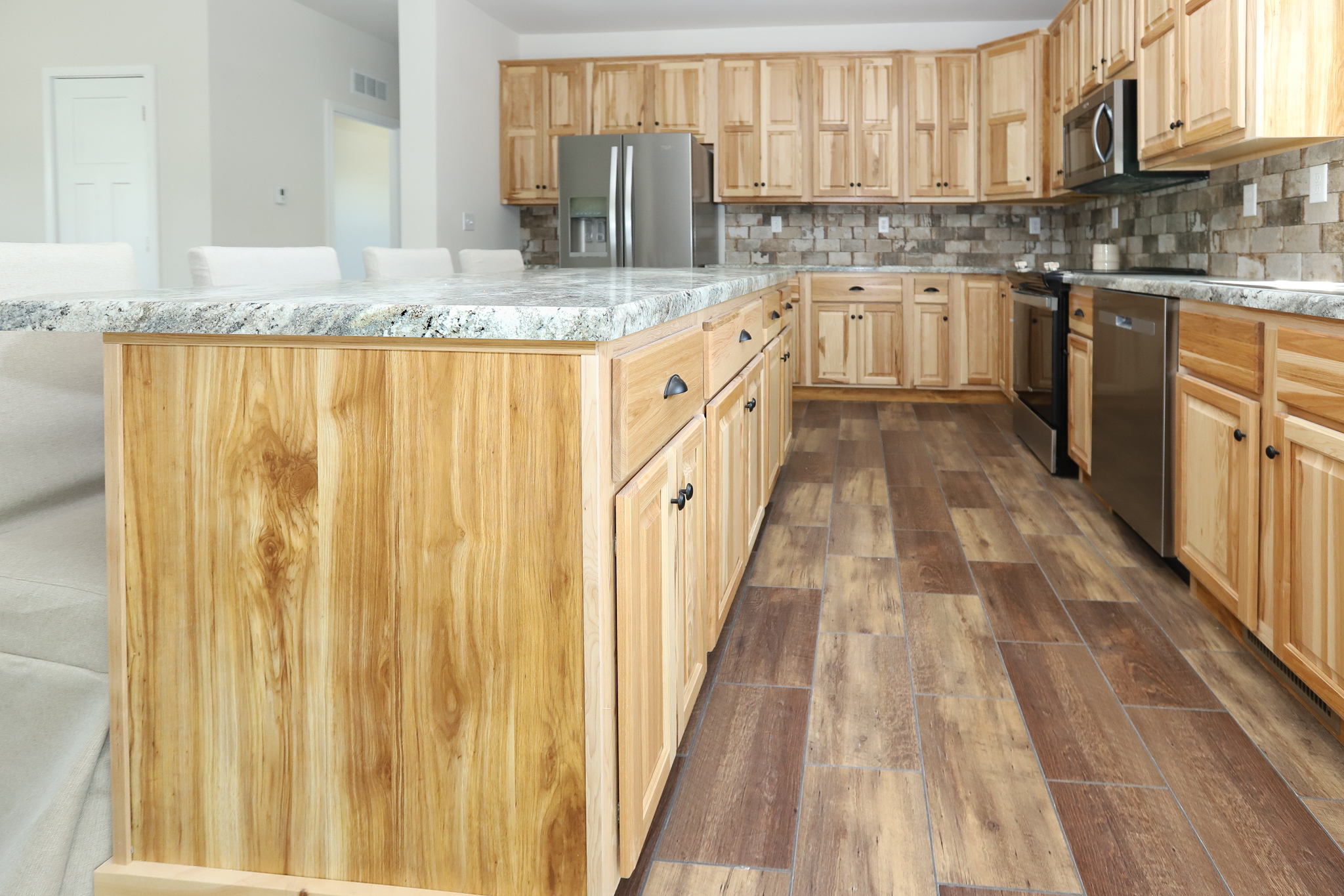 Modern kitchen with wooden cabinets and stone countertops. Stainless steel appliances and light wood flooring create a warm, inviting atmosphere.