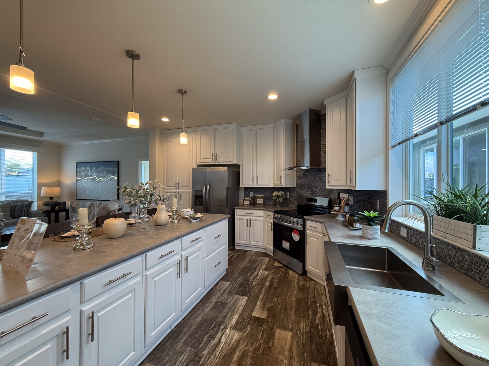 Modern kitchen with white cabinets, stainless steel appliances, and wooden floors. Pendant lights illuminate the island, creating a warm ambiance.