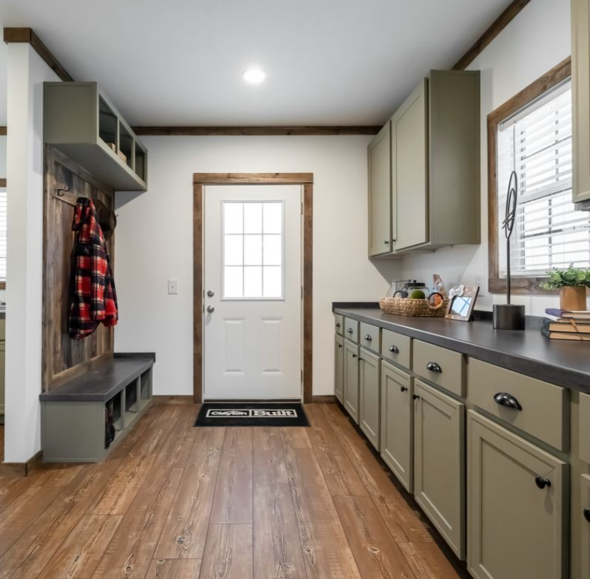 Cozy bedroom with a rustic theme. The bed features earthy-toned pillows and a striped blanket. Two lamps illuminate dark wooden walls, creating a warm, inviting ambiance.