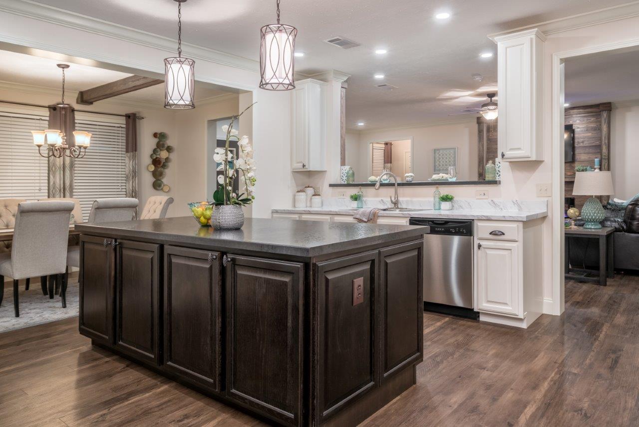 Spacious kitchen with a dark wood island, white cabinets, and stainless steel appliances. Elegant lighting fixtures and dining area create a cozy, modern vibe.