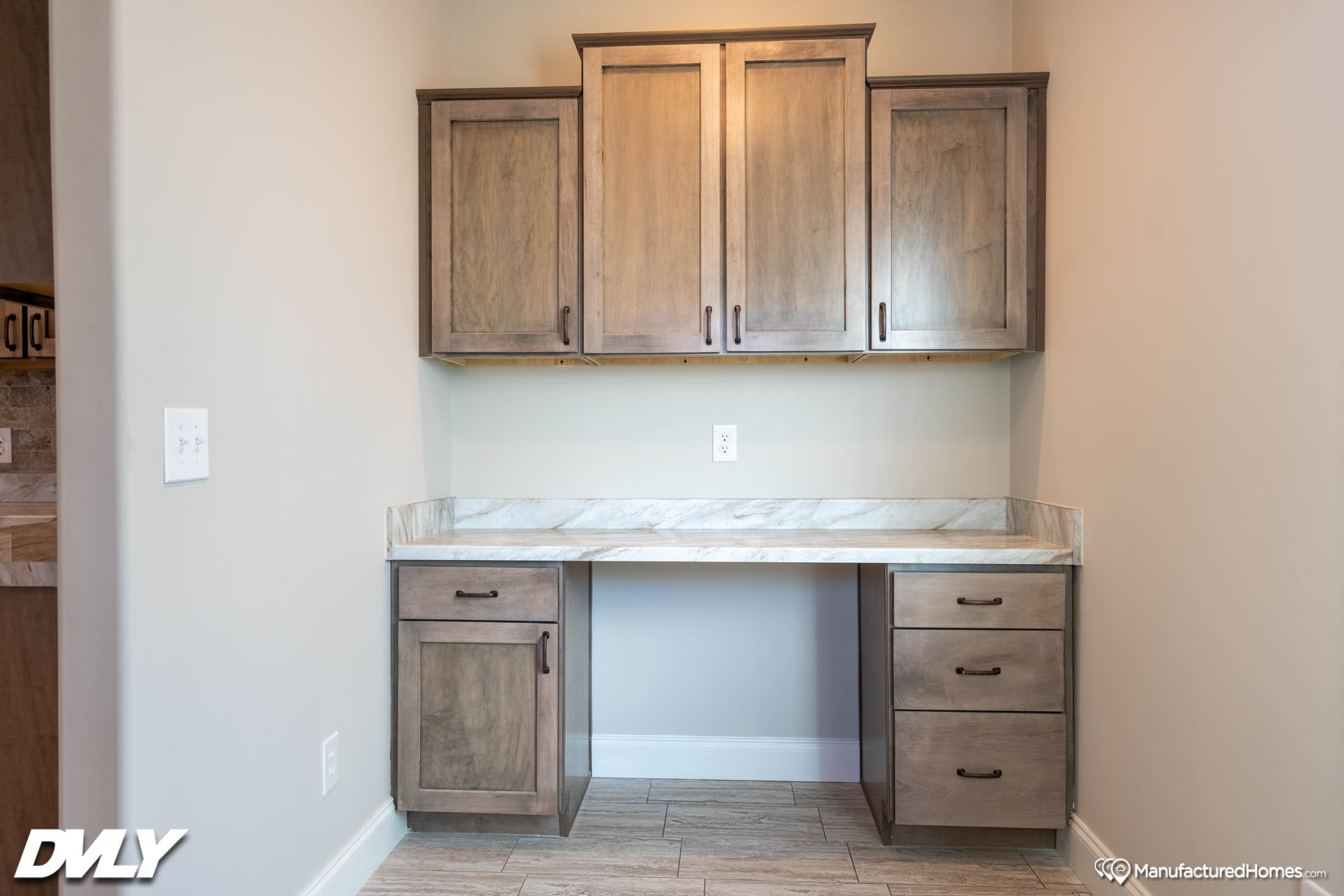 A minimalist work area with a marble countertop, surrounded by light wood cabinets and drawers. Neutral walls add a calm, organized feel to the space.
