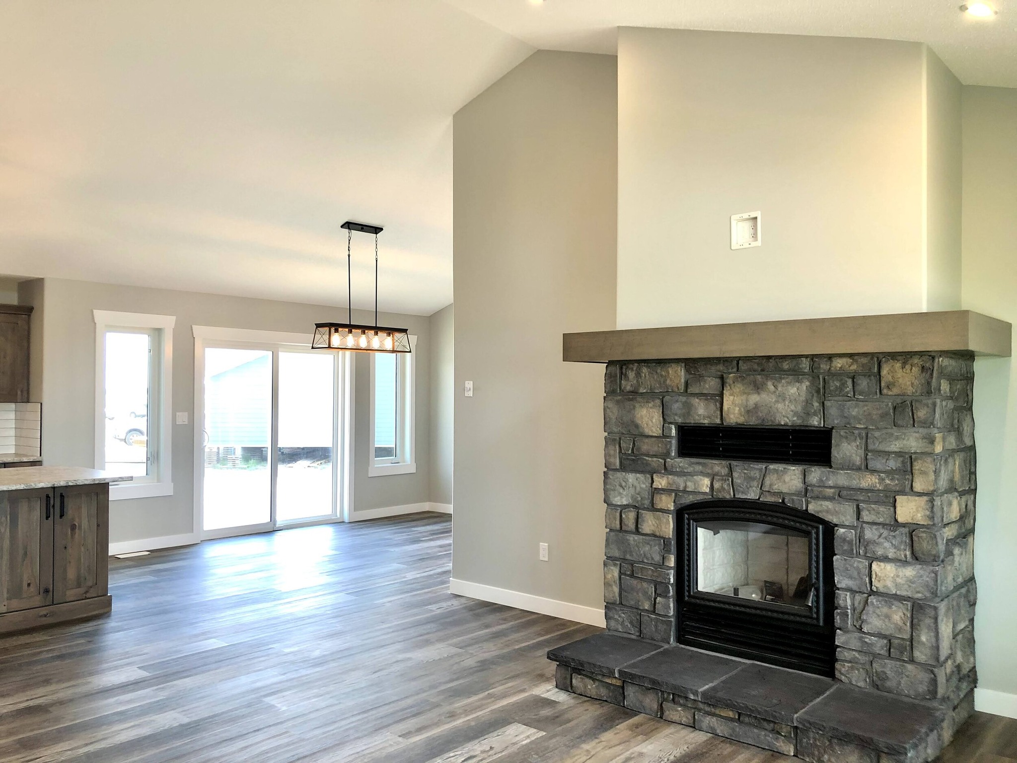 Rustic kitchen with wooden cabinets and a large island with a stone countertop. Features wood flooring, subway tile backsplash, and pendant lighting.