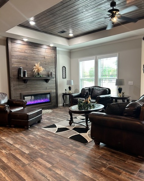 A cozy living room with dark leather sofas, a wooden coffee table, and a modern electric fireplace. Wood accents and patterned rug enhance warmth.