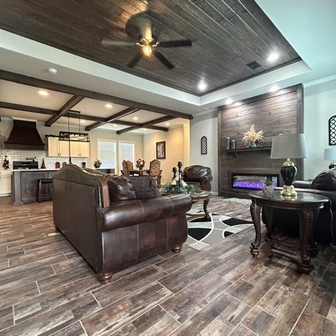 Spacious living room with brown leather sofas, wood floors, and a cozy fireplace. Modern kitchen in background, warm and inviting ambiance.