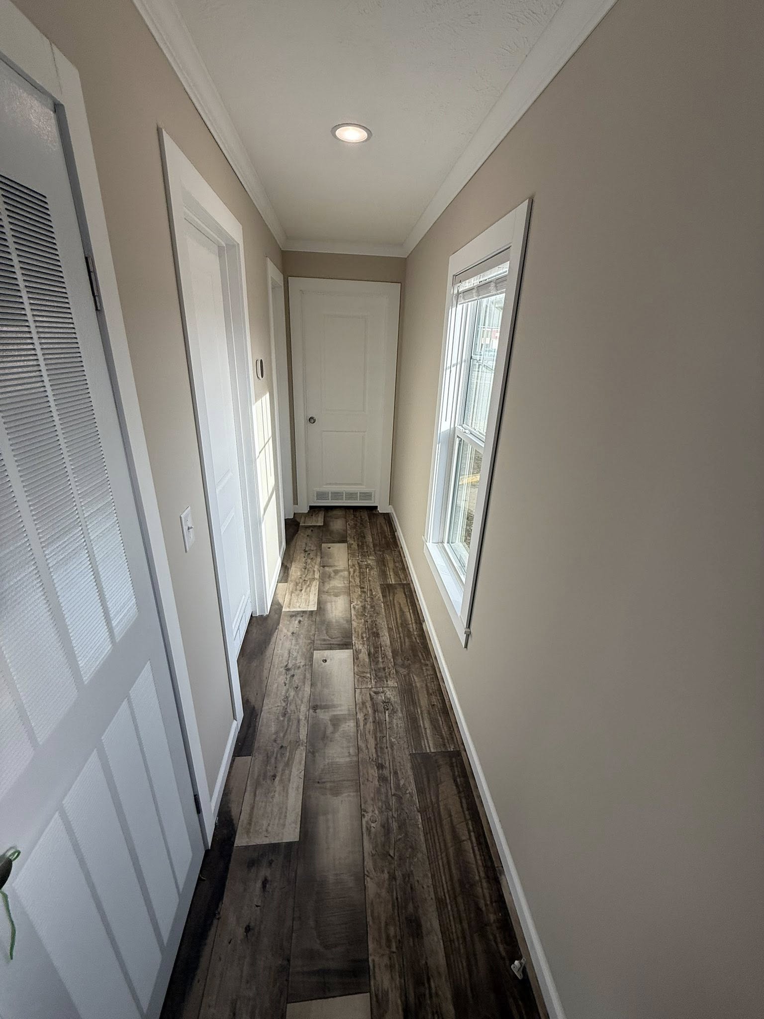 Bathroom shower corner with glossy gray and white tiles arranged in a brick pattern. A shiny chrome shower handle is visible on the left.