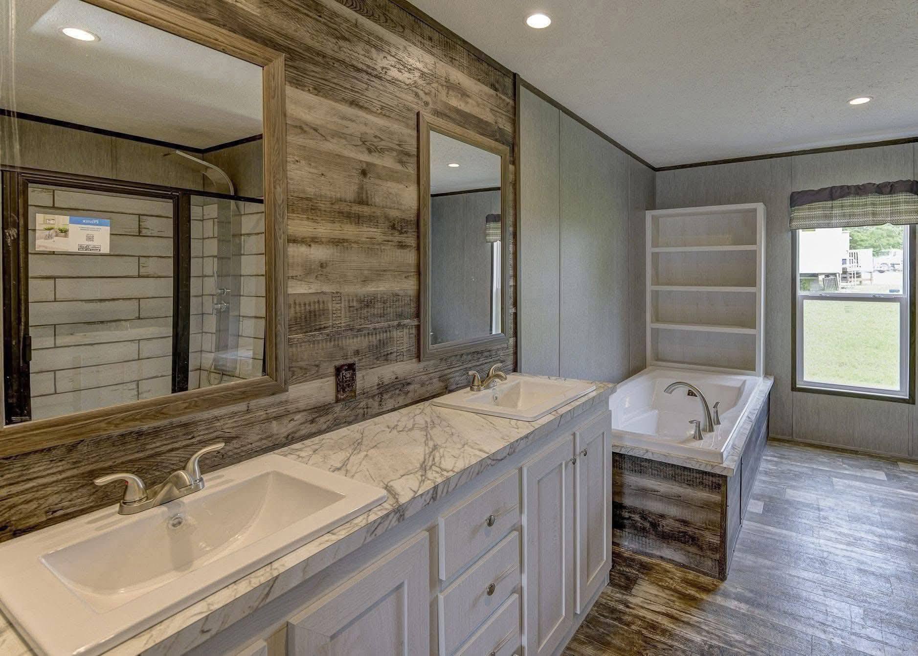 Rustic bathroom with dual sinks set in a marble countertop, wooden wall accents, and an inset bathtub. Natural light from a large window brightens the space.