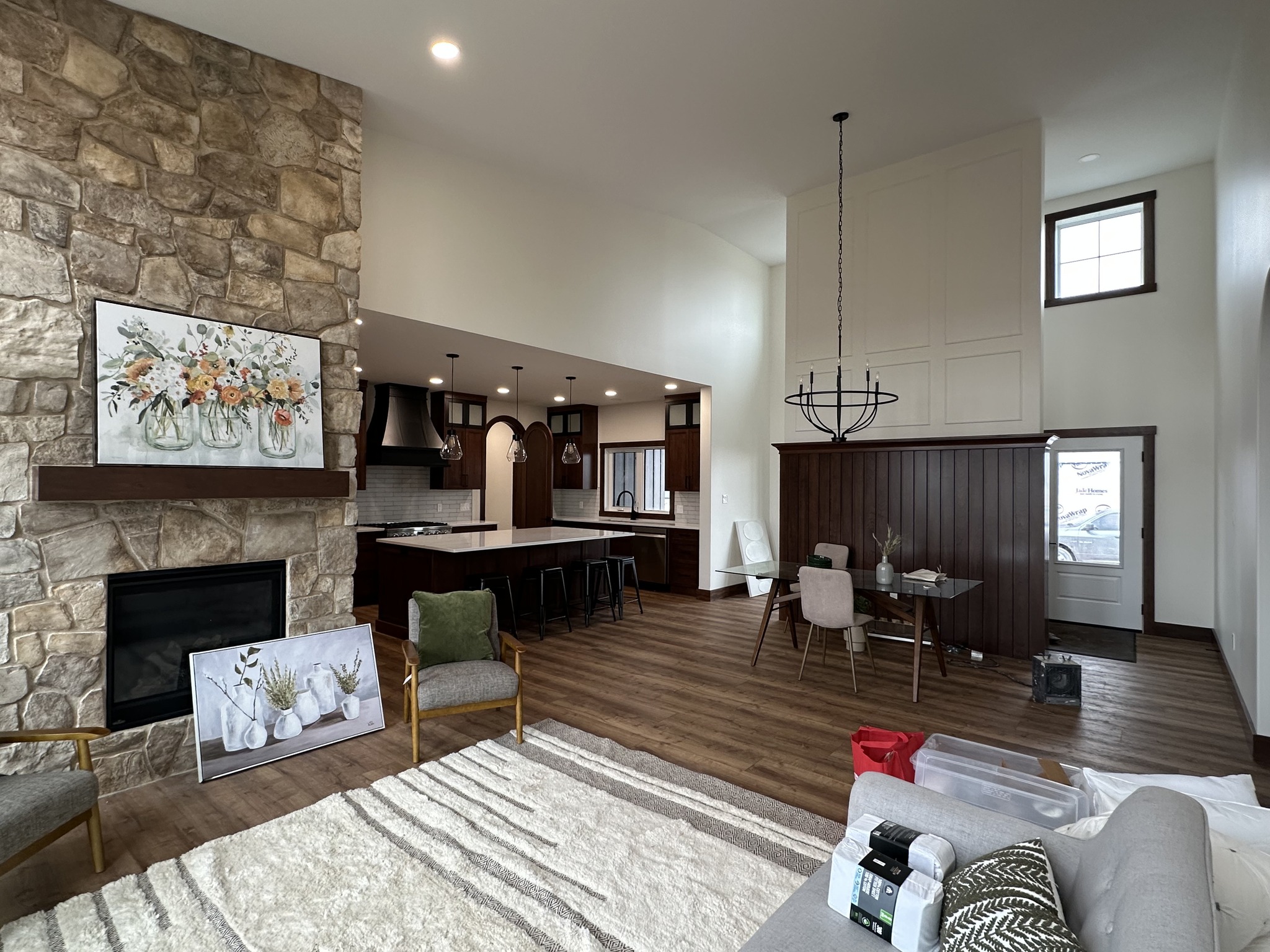 Spacious living area with stone fireplace, cozy seating, and modern kitchen. Bright and inviting with natural light, wooden floors, and elegant decor.