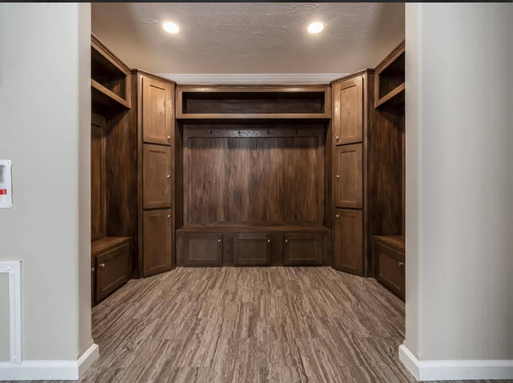 Custom wood mudroom with built-in cabinets and hooks, featuring warm lighting. The sleek, rustic design conveys an organized, cozy atmosphere.