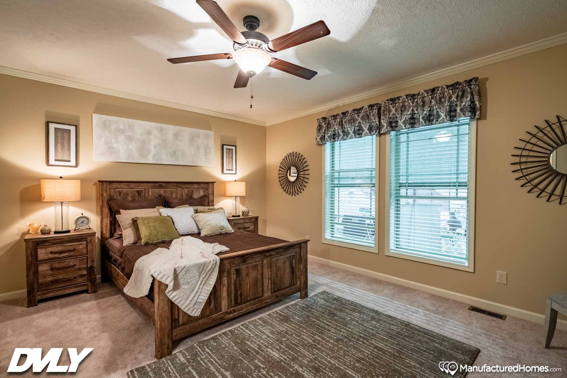 Cozy bedroom with a rustic wooden bed, beige walls, and matching nightstands. Soft lighting, ceiling fan, large windows, and a textured rug enhance warmth.