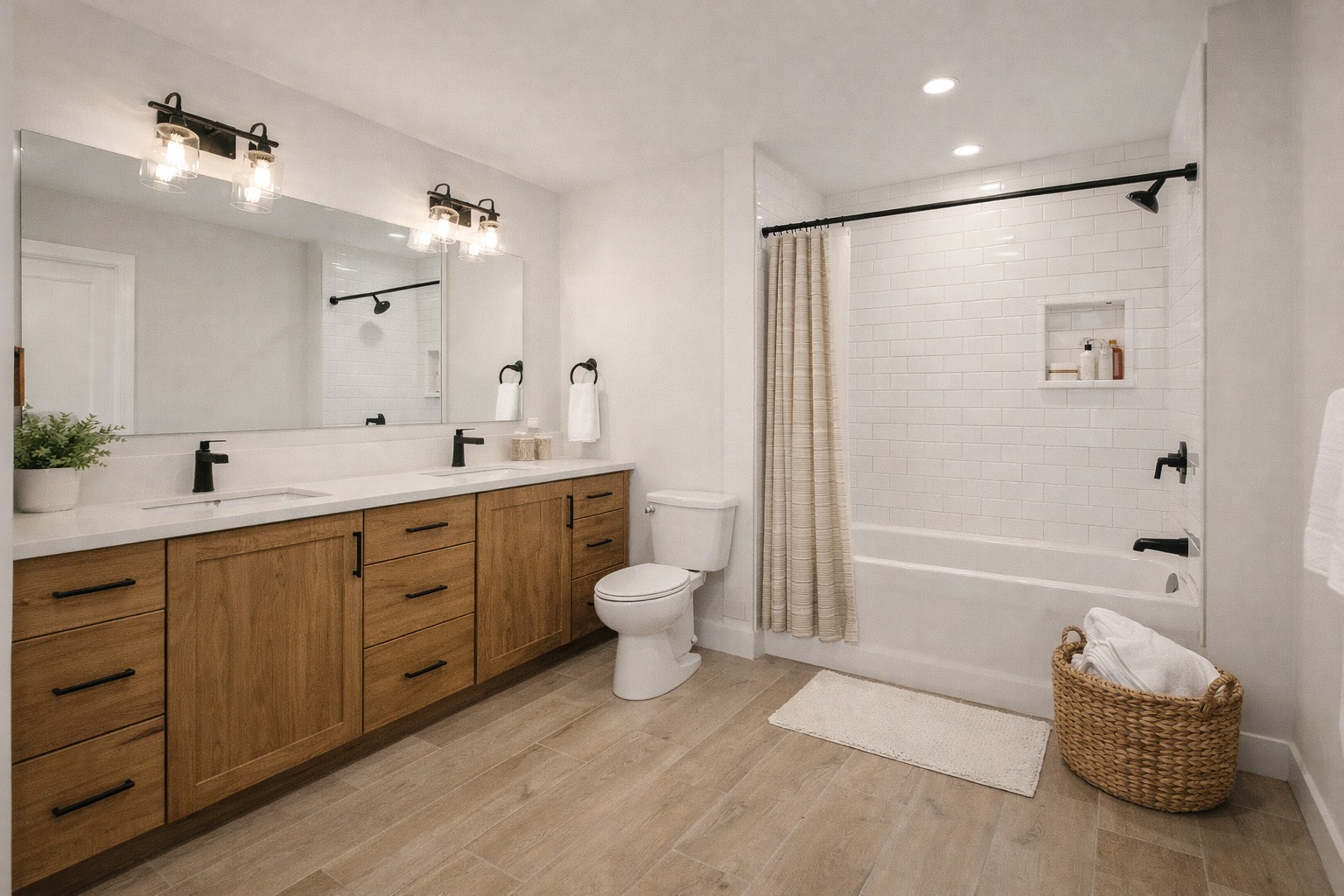Spacious bathroom with wood cabinets, double sink, wall-length mirror, and warm lighting. Features a white subway tile bathtub, and wicker basket on wood floor.