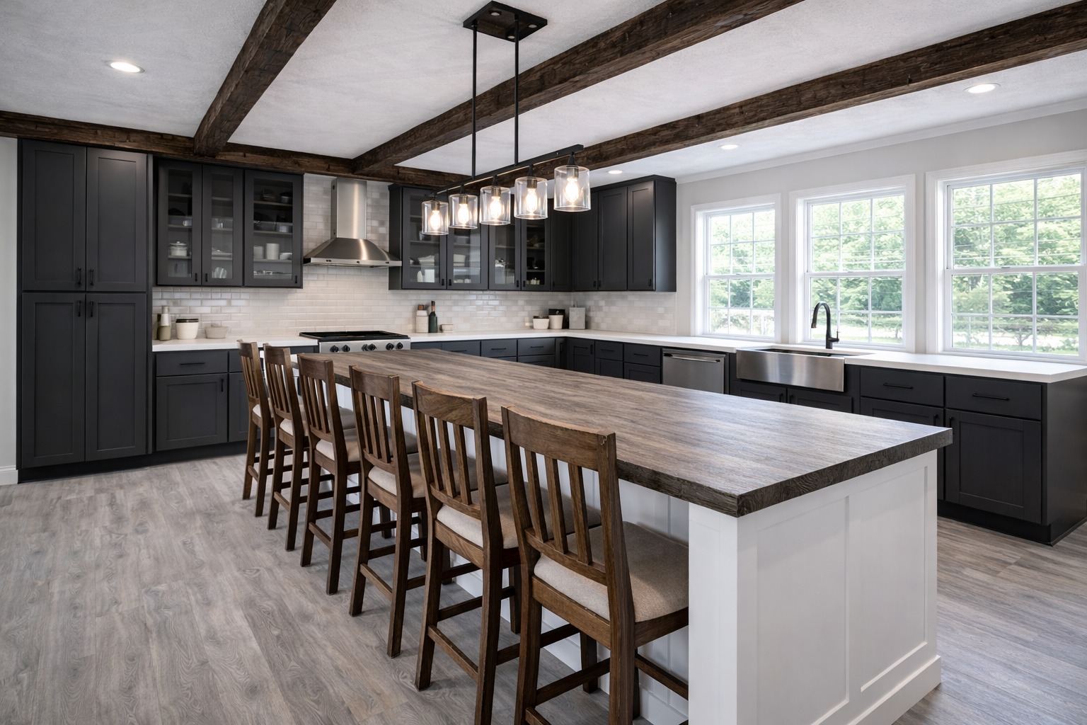 Spacious kitchen with dark cabinets, white countertops, and a long wooden island with eight chairs. Pendant lights hang from wooden beams, creating a rustic yet modern feel.