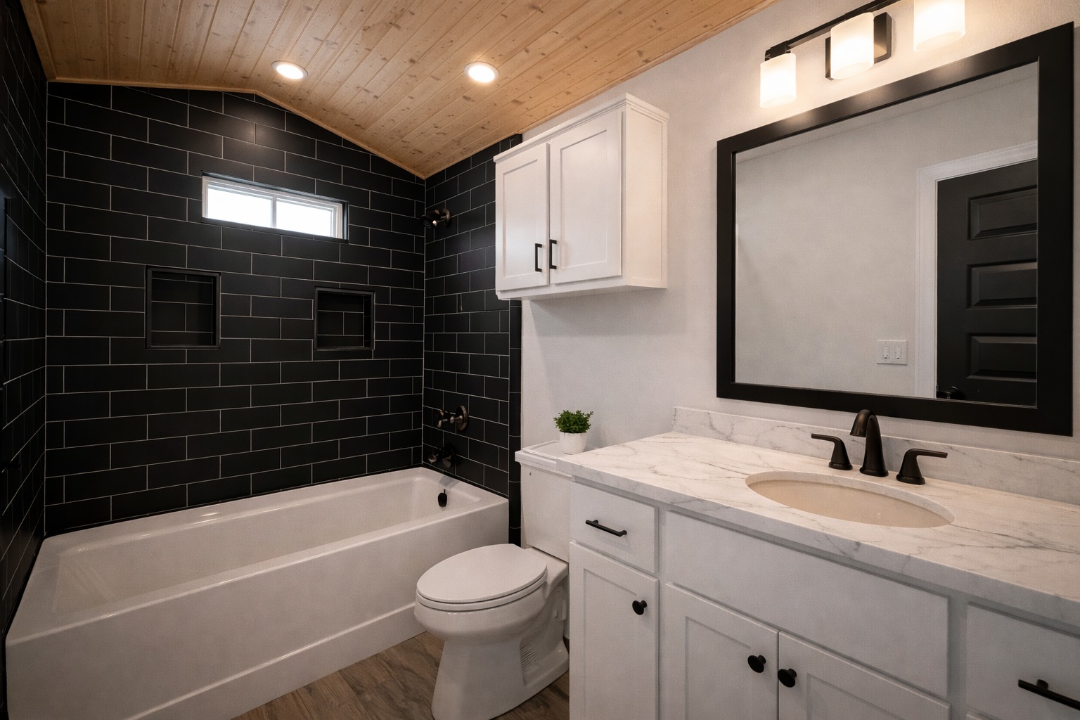 Modern bathroom with a marble countertop, black fixtures, white cabinets, and a black-tiled wall. Soft lighting and a wooden ceiling add warmth.
