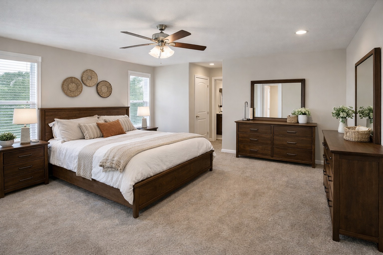 A cozy bedroom with a wooden bed frame, neutral bedding, and throw pillows. Two nightstands, a large dresser with plants, and wall baskets add warmth.