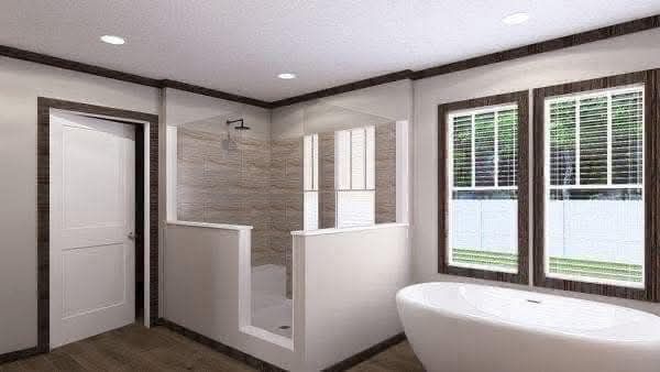 Modern bathroom with a freestanding tub below two large windows, a walk-in shower with partial walls, wooden flooring, and recessed lighting, creating a serene ambiance.