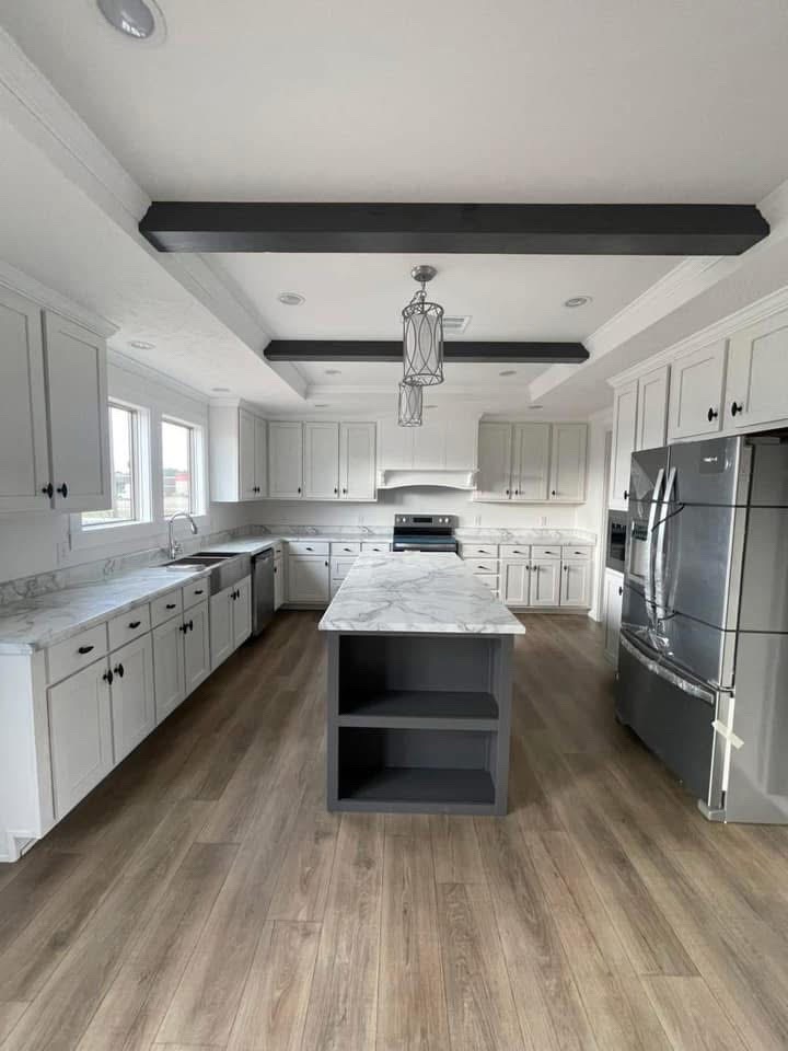 Spacious modern kitchen with white cabinets, marble countertops, and a central island. Stainless steel appliances and wooden floors add elegance.