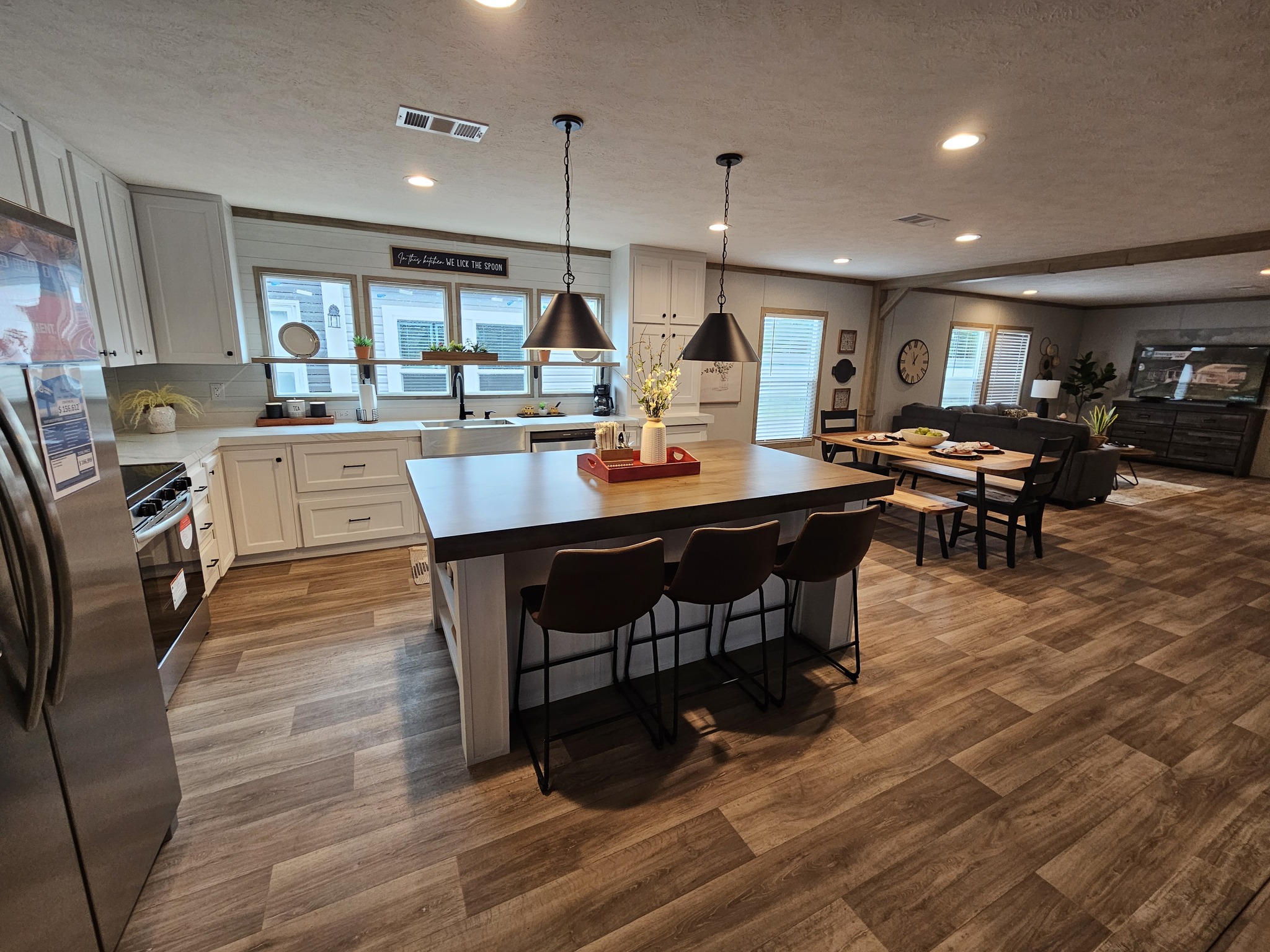 Spacious kitchen and dining area with wood flooring, white cabinets, and large island. Black pendant lights hang over the island. Cozy, modern vibe.