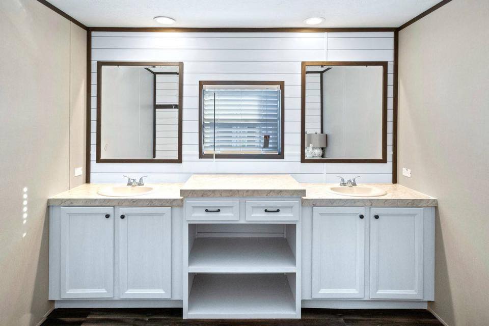 Modern bathroom with double sink vanity, white cabinets, and beige countertops. Three mirrors display a clean, minimalistic design with soft lighting.