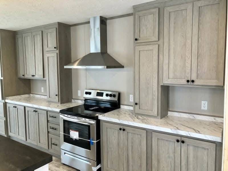Modern kitchen with light gray cabinets, marble countertops, and a stainless steel stove and range hood. The space is sleek and minimalistic.